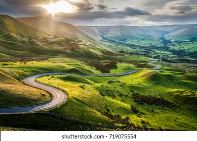 Sunset at Mam Tor, Peak District National Park, with a view along the winding road among the green hills down to Hope Valley, in Derbyshire, England. - Shutterstock ID 719075554