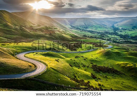 Sunset at Mam Tor, Peak District National Park, with a view along the winding road among the green hills down to Hope Valley, in Derbyshire, England.