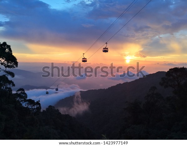 Sunset from a mountain with cable cars floating above\
cloud! 