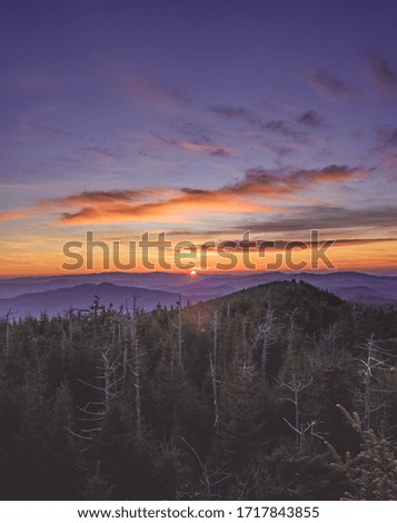 The sunset of mountain layers viewing from Newfound Gap in Great Smoky Mountains National Park. The sunset makes a gradient tone of purple, yellow, and blue. This shot is taken in November, late fall.