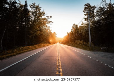 sunset in the mountains with houses close to the river, layers of the mountains, solitary road with the bright sun in the background - Powered by Shutterstock