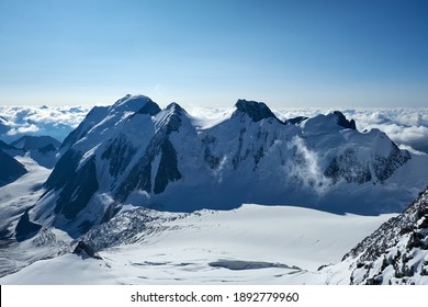 Sunset in mountains. Reflection of red sun on mountain snow peaks and clouds. Altai, Belukha area.