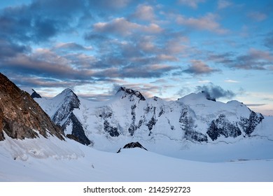 Sunset in mountains. Reflection of red sun on mountain snow peaks and clouds. Altai, Belukha area.