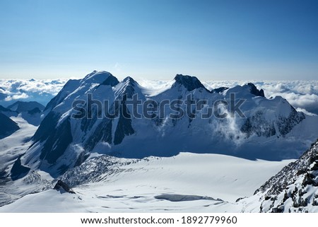 Sunset in mountains. Reflection of red sun on mountain snow peaks and clouds. Altai, Belukha area.