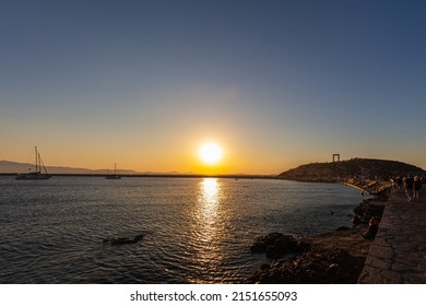 Sunset in Naxos Bay. The red and yellow glowing sun sinks on the horizon. Boats anchor and lie off the coast. Romantic scene in the Cyladen archipelago in the Aegean Sea. Sunset at the sea - Shutterstock ID 2151655093