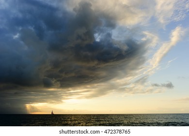 Sunset Ocean Sailboat Journey Is A Small Boat Sailing Towards The Light Of Adventure, Faith, Freedom And Hope As An Approaching Surreal Storm Looms Overhead.