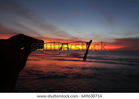 Sunset and ocean through glasses in a hand