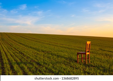 Sunset With Old Chair In The Spring Field. Relaxing On The Empty Field At Sunset.