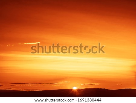 Sunset on Baikal lake with sun setting down behind the mountain and sun rays 