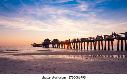 Sunset on the beach at Naples Pier in Naples, Florida.