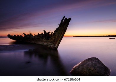 Sunset on the beach with an old sailboat wreck.The "Raketa" ship wreck on the Loksa beach in Estonia. The ship was built in 1949 in Finland