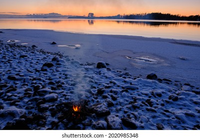 Sunset On The Beach With Snow And Campfire In The Foreground