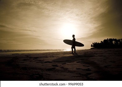 Sunset on the beach with surfer watching waves. - Powered by Shutterstock