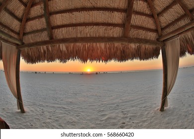 Sunset on the beach under a tiki hut - Powered by Shutterstock