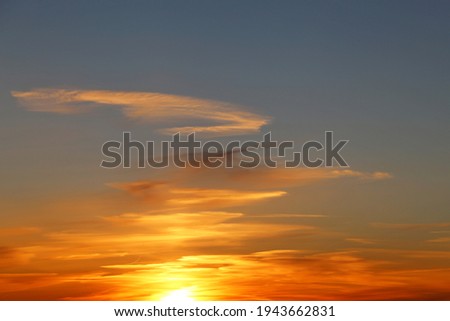 Sunset on colorful dramatic sky, white clouds in the orange sunlight. Picturesque landscape for background