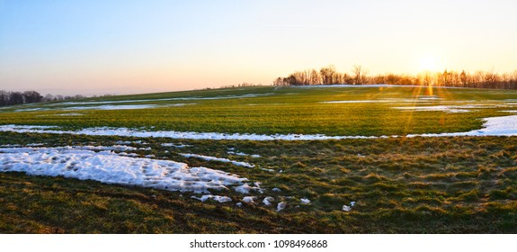 Sunset On The Field Covered With Melting Snow