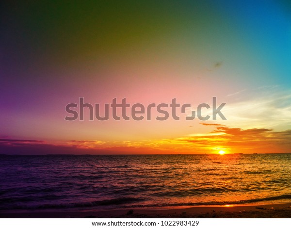sunset on horizon line over sea and colorful sky\
in evening