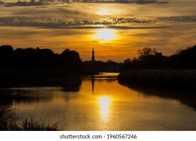 Sunset on the Nete with the silhouette of the village center of Duffel in the background