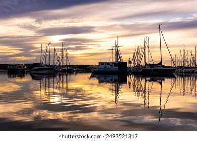 Sunset on the pier of Lake Cospuden near Leipzig. Sailing boats in the harbor. golden sky with reflections on the water. Local recreation in the Leipzig area.  - Powered by Shutterstock