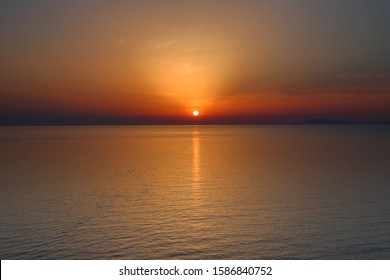 Sunset on the sea with the sun over the horizon that spreads a warm color on the sea and on the sky. Red, blue, violet and grey colors create a dreaming atmosphere of vacation and rest. - Shutterstock ID 1586840752