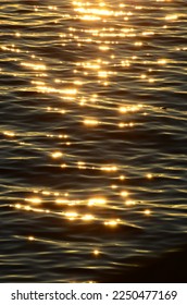 Sunset on the wave. Shiny. Rippled golden sea water surface glistening in sunlight.