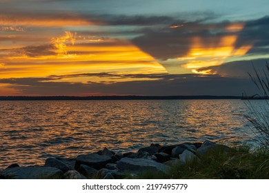 A Sunset On The York River In Gloucester, Virginia, With Rocks And Beach