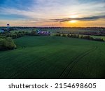 Sunset over agricultural fields in rural Kentucky between cities of Lexington and Nicholasville with a barn between tree lined pastures.