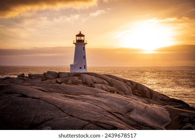 Sunset over the Atlantic Ocean at Peggy's Cove, Nova Scotia near Halifax with the iconic lighthouse in the foreground.