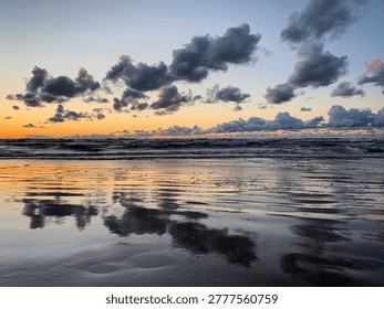 Sunset over the Baltic Sea with dramatic clouds reflecting on the wet sand, Jūrmala, Vidzeme, Latvia, July 2020