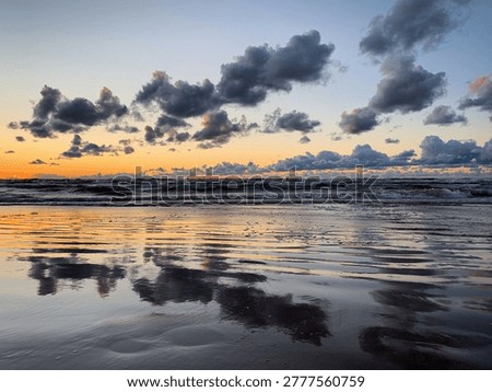 Sunset over the Baltic Sea with dramatic clouds reflecting on the wet sand, Jūrmala, Vidzeme, Latvia, July 2020