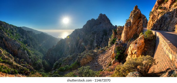 Sunset over Calanques de Piana with road through mountains in foreground, Corsica, France. - Powered by Shutterstock