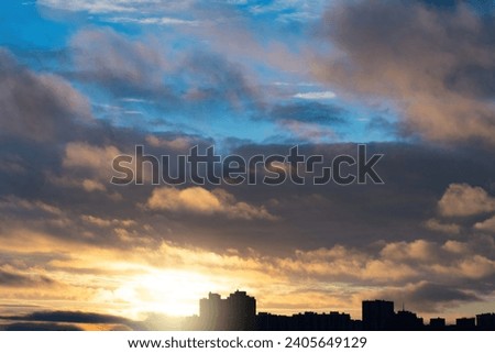 Sunset over city. City buildings under evening sky. Dawn over metropolis. Silhouettes of evening buildings at sunset. Summer sky with clouds. Beautiful city scape with sunset. Cityscape, cityline