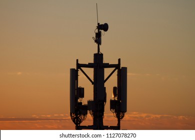 Sunset Over The City. Mobile Tower, Cell Tower. Industrial Landscape. Bright Sunset Over The Horizon