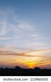 Sunset Over The City. View From Above. The Sky Is Yellow And Pale Blue. No People. In The Background The Contours Of The City. Photo Color, Vertical.