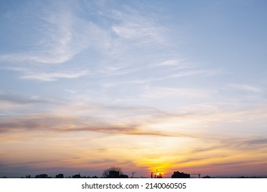 Sunset Over The City. View From Above. The Sky Is Yellow And Pale Blue. No People. In The Background The Contours Of The City.Photo Horizontal, Color.