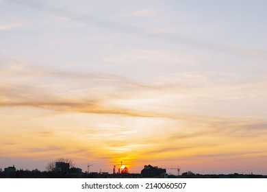 Sunset Over The City. View From Above. The Sky Is Yellow And Pale Blue. No People. In The Background The Contours Of The City.Photo Horizontal, Color.