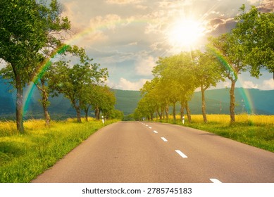 sunset over deciduous trees along the country road in to mountains. beautiful summer landscape of a slovakia countryside. beautiful travel background. journey through europe. weather with rainbow