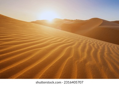 Sunset over the desert of Al Khatim in Abu Dhabi, Emirates. Golden Sand Dune Desert Landscape Panorama. Beautiful sunset over the sand dunes in the Al Khatim in Abu Dhabi, Emirates