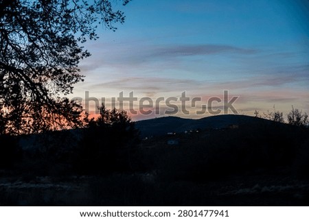 Sunset over distant hills with silhouetted trees
