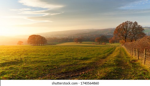 Sunset over farmland, meadows and trees in autumn with golden brown leaves on the trees in England, UK.