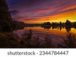 Sunset over a forest lake. Forest lake at sunset. Sunset lake water. Lake water reflection at sunset