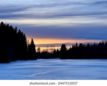 Sunset over frozen lake in the Norwegian winter forest. Ice and silhouette pine trees. Norway - Powered by Shutterstock