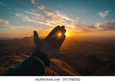 Sunset Over A Hill Penetrating The Palm Of A Young Man Enjoying This Moment Full Of Color And Silence Around Him.