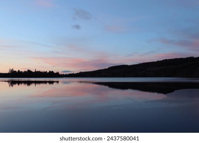 Sunset over an icy lake in winter, with colourful light reflections in still water - Powered by Shutterstock