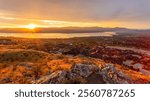 Sunset Over Kelowna and Okanagan Lake. View of Kelowna at sunset with warm colours illuminating the sky and reflecting on foreground.