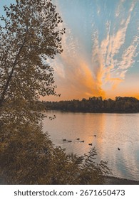Sunset over the lake with ducks and dramatic sky.