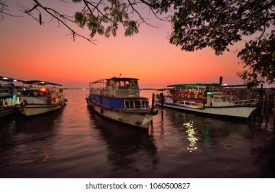 Sunset over lake Vembanad in Marine Drive, Kochi with tourist boats in the background