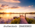 Sunset over the lake in the village. View from a wooden bridge, image in the orange-purple toning