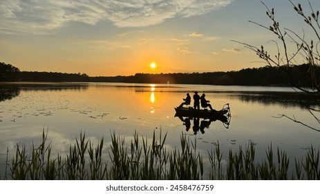 Sunset over a large lake with silhouette of people fishing on the boat. - Powered by Shutterstock