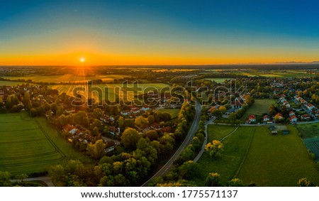 Sunset over a little town, orange sunbeams illuminate the houses. Beautiful time of a springday.